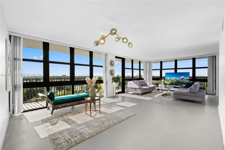 Expansive open-concept room featuring floor-to-ceiling black-framed windows, neutral polished flooring, and a multi-globe architectural chandelier