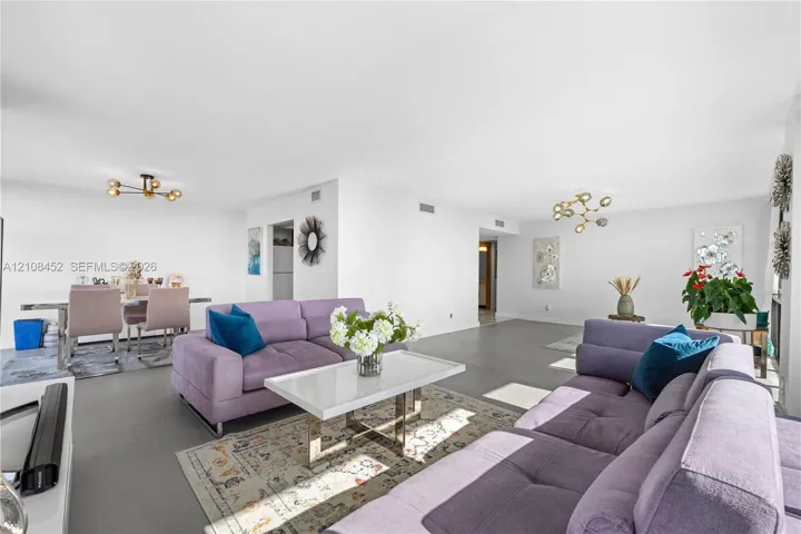Open-concept interior featuring smooth flooring and two multi-arm modern light fixtures