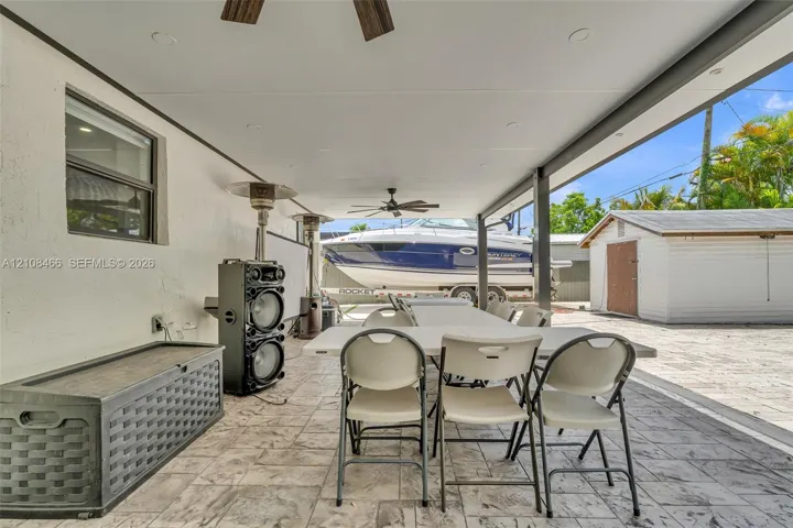 Covered patio featuring stamped concrete flooring, a ceiling fan, and recessed lighting, with an exterior storage structure