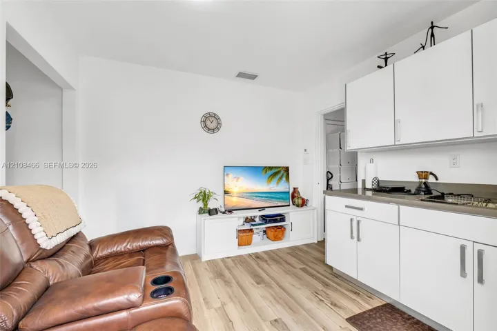 Kitchenette featuring white cabinetry with silver-tone hardware, solid-surface countertops, and wood-finish flooring