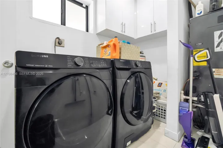 Dedicated utility area featuring white shaker-style cabinetry with brushed nickel hardware and a window for natural light
