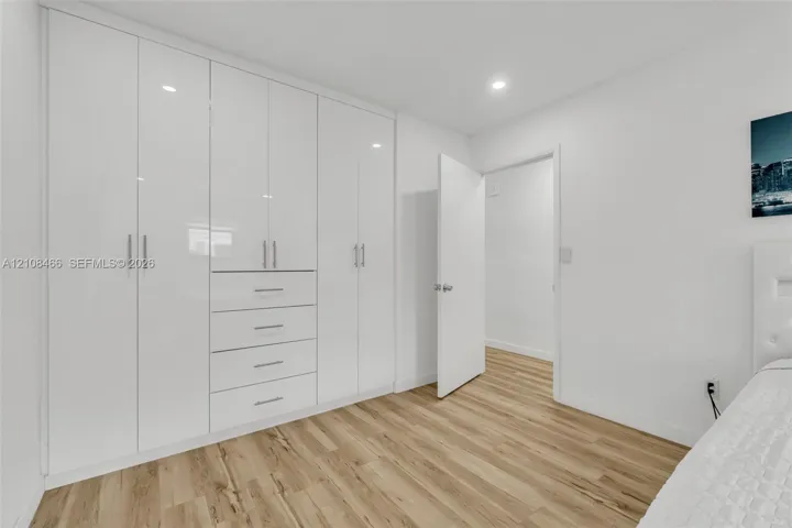Built-in floor-to-ceiling cabinetry with white high-gloss finish, integrated drawers, brushed metal hardware, and wood-finish flooring