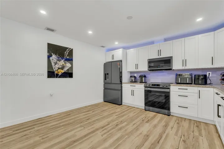 Kitchen featuring shaker-style white cabinetry, wood-finish flooring, recessed lighting, and stainless-steel appliances
