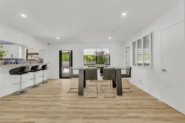 Open floor plan featuring wood-finish flooring, recessed lighting, and a kitchen breakfast bar with stone-surfaced countertop