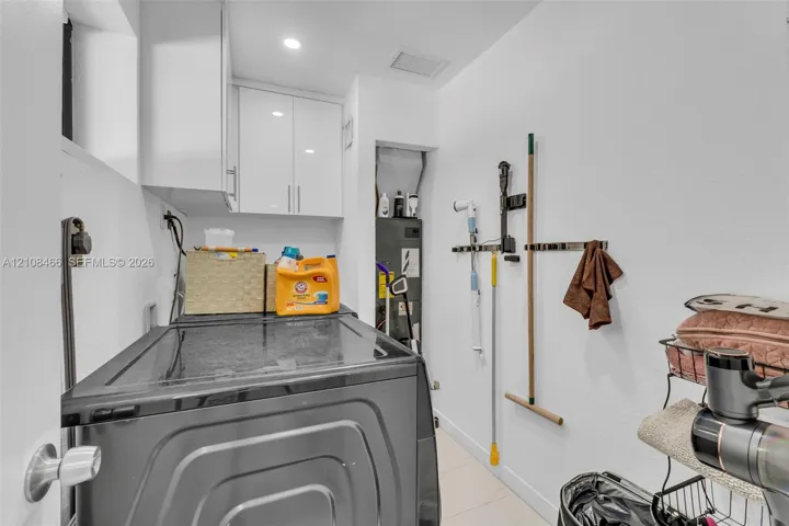 Utility room featuring white shaker-style wall-mounted cabinetry, recessed lighting, and wall-mounted storage tracks