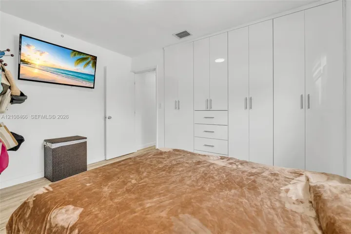 Floor-to-ceiling white cabinetry featuring integrated drawer storage, sleek vertical hardware, and wood-finish flooring