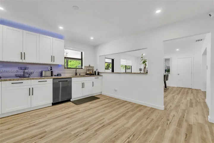 Kitchen featuring white shaker-style cabinetry, stone-finish countertops, wood-finish flooring, recessed lighting, and a stainless steel dishwasher
