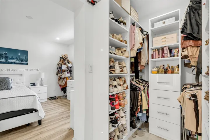 Custom walk-in closet featuring floor-to-ceiling white shelving, integrated cabinetry with four drawers, and recessed lighting