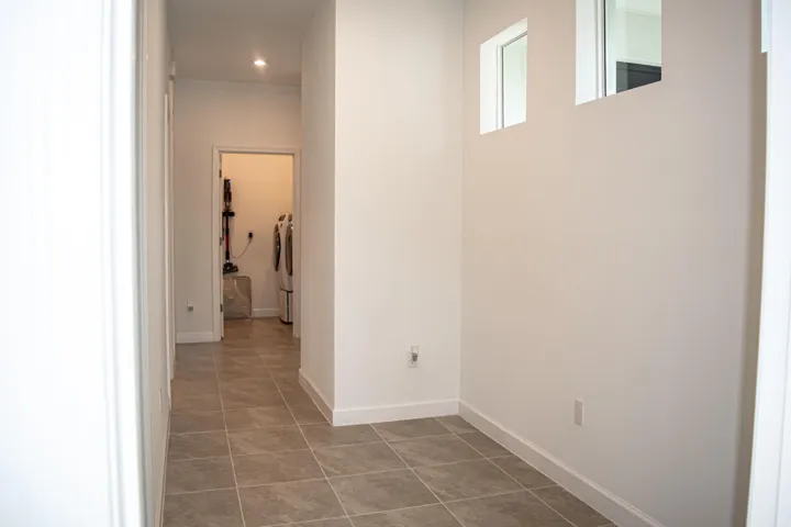 Neutral-toned ceramic tile flooring, high-placed square windows, and recessed lighting