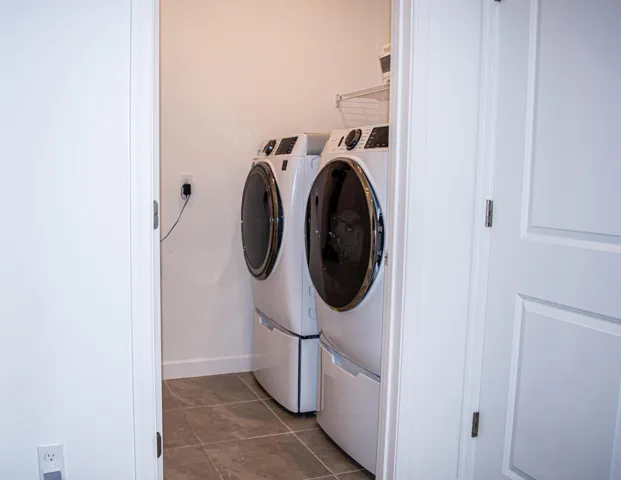 Laundry area featuring tile flooring, white-finish cabinetry, and wire shelving