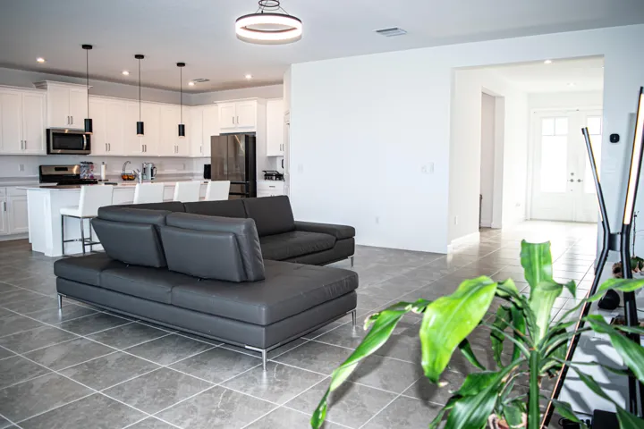 Open-concept kitchen featuring white shaker-style cabinetry, quartz countertops, a kitchen island, recessed lighting, and large-format tile flooring