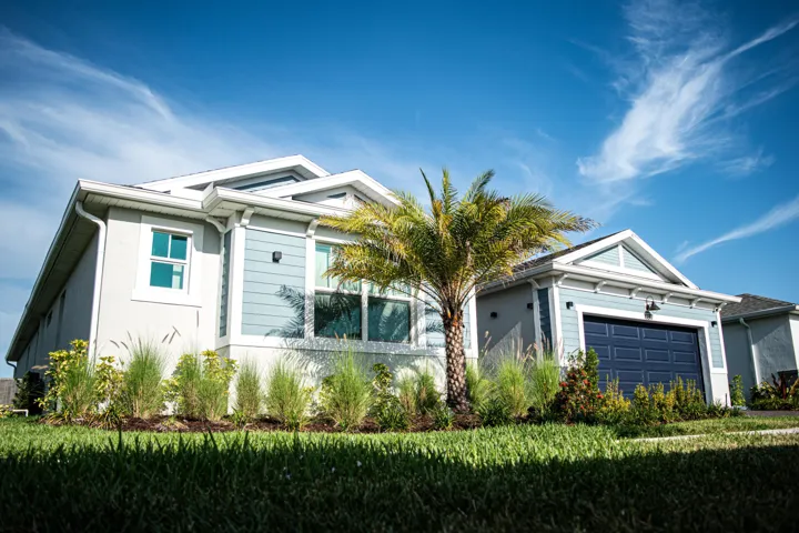 Exterior featuring horizontal lap siding, a gabled roofline, an attached two-car garage, and landscaped garden beds with established ornamental grasses