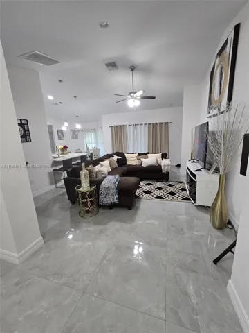 Large-format polished tile flooring, high ceilings, integrated recessed lighting, and a ceiling fan with light kit