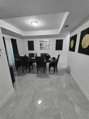 Tray ceiling featuring a central flush-mount light fixture and large-format tile flooring with a polished finish