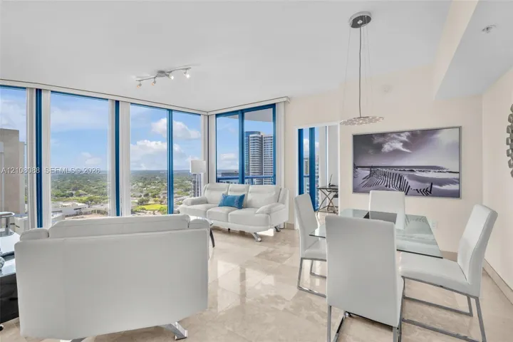 Open-concept space featuring floor-to-ceiling windows, polished stone flooring, and suspended pendant lighting
