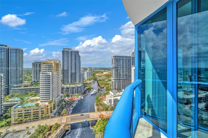 Private balcony with blue glass railing featuring floor-to-ceiling blue-tinted windows and stone-tiled flooring