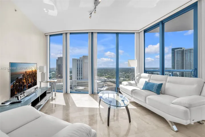 Floor-to-ceiling windows, polished stone flooring, and track lighting