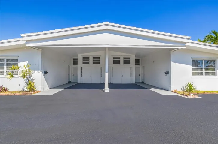 Front of Property, Single-story exterior featuring white stucco siding, a covered central carport, multi-pane windows, and glass block accents