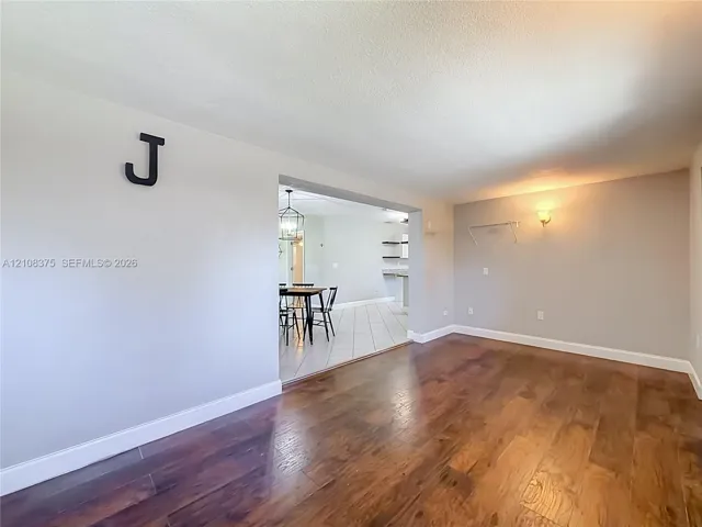 Room featuring wood-finish flooring, neutral wall paint, and wall-mounted lighting