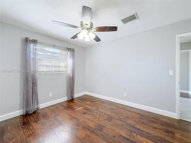 Wood-finish flooring, neutral wall tones, and a ceiling fan with integrated lighting