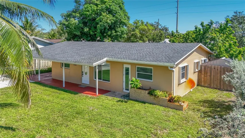 Single-story exterior featuring a covered carport, shingled roof, horizontal siding, masonry planter box, and a fenced backyard