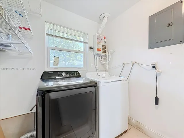 Laundry area featuring a tankless water heater, electrical panel, and mounted wire shelving