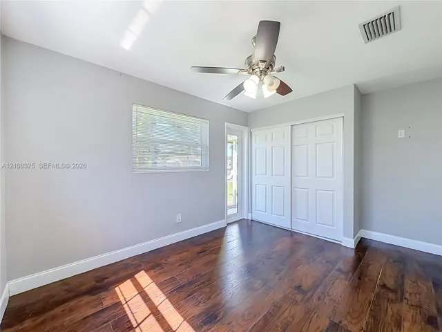 Room featuring wood-finish flooring, a ceiling fan with integrated lighting, a sliding closet with paneled doors, and a glass-paneled exterior door
