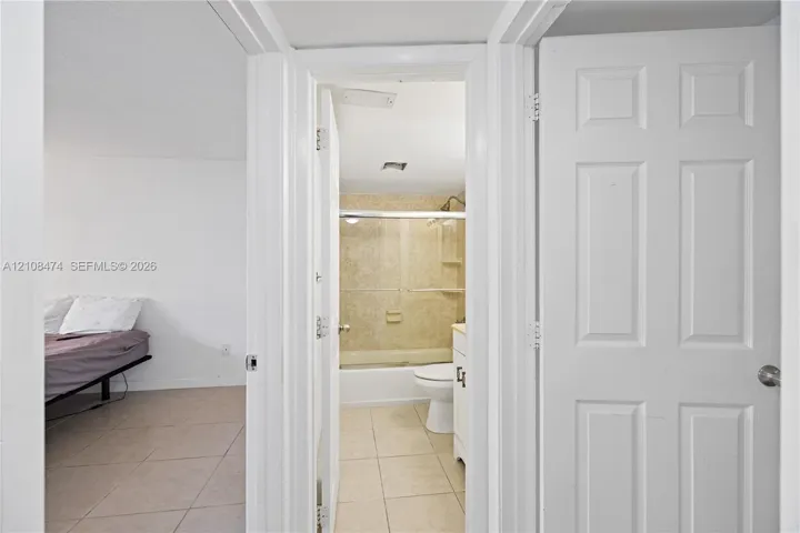 Bathroom featuring a tub-shower combination with sliding glass doors, tile flooring, and a white vanity