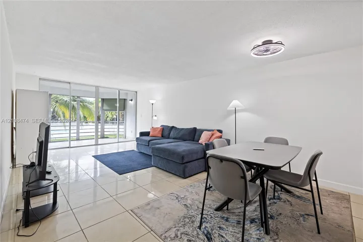 Open-concept living space featuring high-gloss tile flooring, floor-to-ceiling sliding glass doors, and a flush-mount ceiling light fixture with an integrated fan
