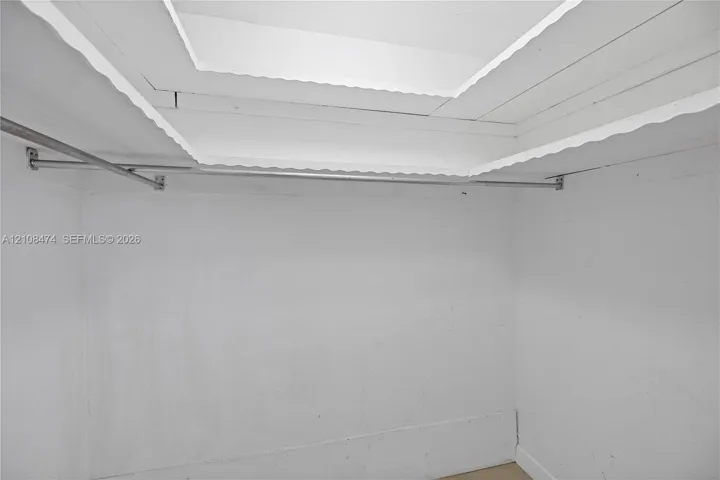 Storage area featuring a tray ceiling with recessed lighting and a wall-mounted metal garment rod