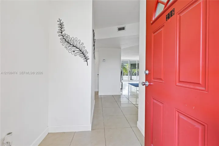 Entryway featuring a solid-panel door with arched glass inlay, neutral-toned tile flooring, and clean-finish walls