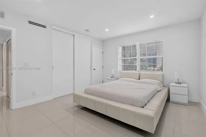 Neutral-toned tile flooring, recessed ceiling lighting, multi-pane windows, and dual sliding closet doors