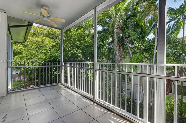 Screened-in balcony featuring tile flooring, white metal railing, and a ceiling fan