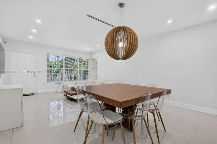 Large-format neutral tile flooring, recessed ceiling lighting, and a spherical wood-slat pendant fixture