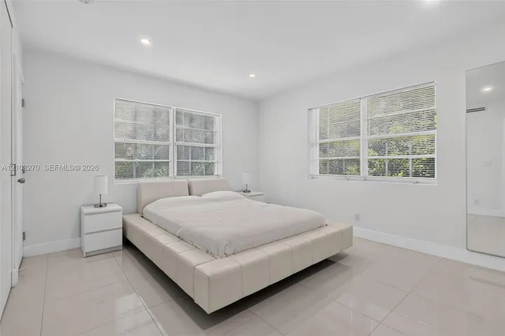 Neutral-toned tile flooring, recessed ceiling lighting, and large dual-pane windows with integrated blinds