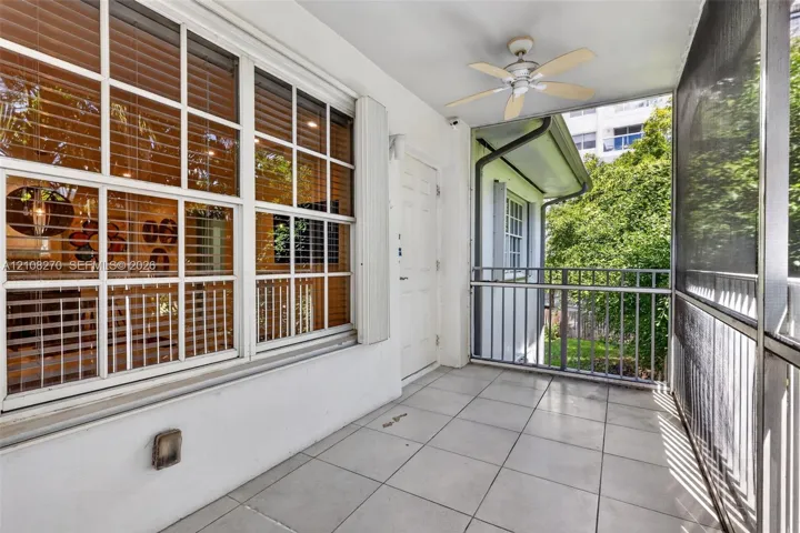 Screened-in balcony featuring tile flooring, a ceiling fan, and metal railings