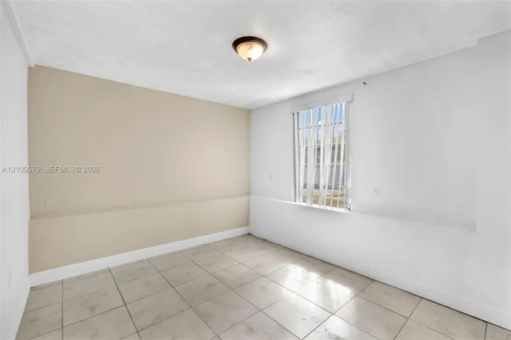 Neutral-toned interior space featuring tile flooring, a dual-tone wall finish, and a flush-mount ceiling light