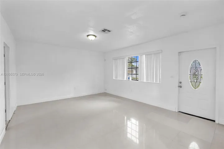 Neutral-toned tile flooring, large multi-pane windows, and an entry door featuring an oval decorative glass insert