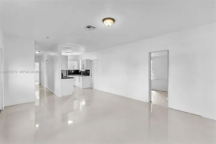 Interior space featuring neutral wall tones, large-format tile flooring, recessed and flush-mount ceiling lighting, and kitchen cabinetry with contrasting countertops