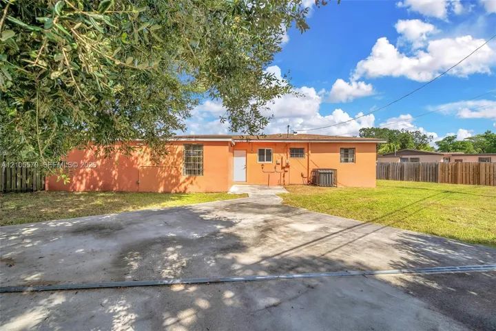 Exterior of the residence featuring a concrete driveway, masonry walls, horizontal fencing, and a concrete patio