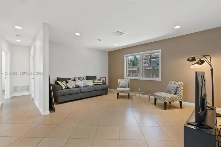 Neutral-toned interior space featuring light-colored ceramic tile flooring, recessed ceiling lighting, and a prominent dual-tone wall finish