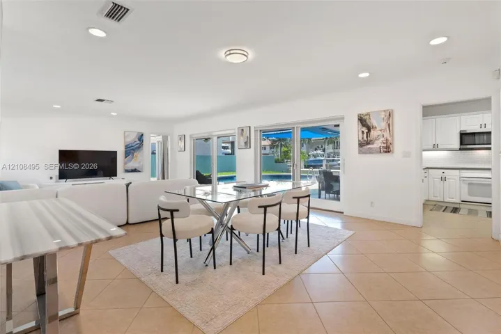 Open-concept interior featuring large-format tile flooring, recessed lighting, and multiple sliding glass doors providing outdoor access