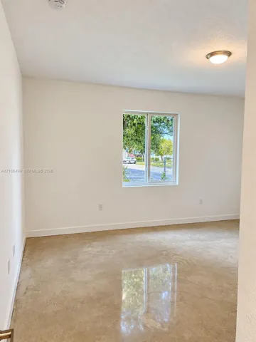 Interior space featuring polished concrete flooring, neutral wall tones, a single-pane window, and a flush-mount ceiling light fixture