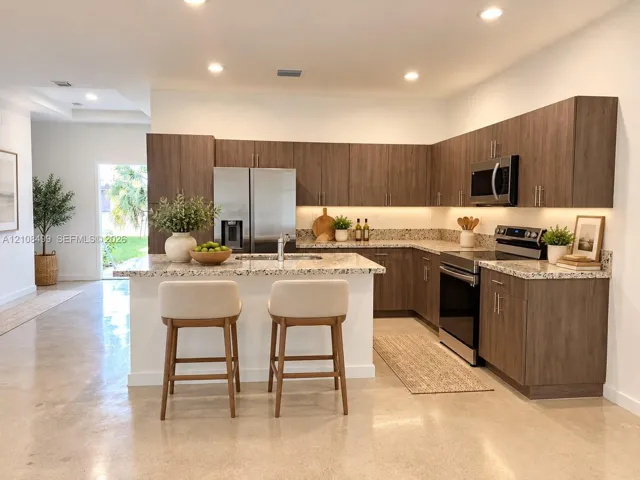 Kitchen featuring wood-finish cabinetry, stone-surface countertops, stainless steel appliances, under-cabinet lighting, and polished concrete flooring