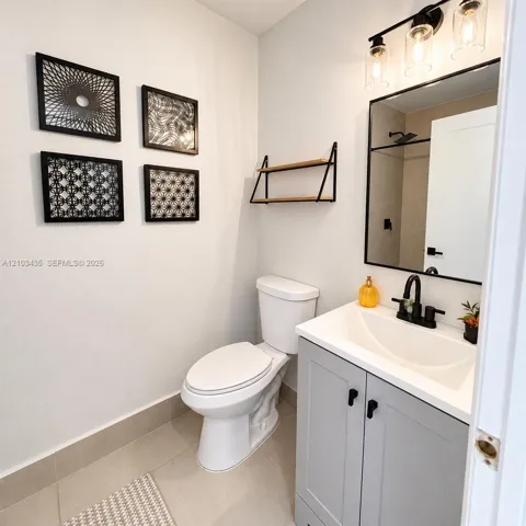 Grey vanity featuring a white basin, matte black faucet, rectangular mirror with a black frame, and glass-shade light fixture