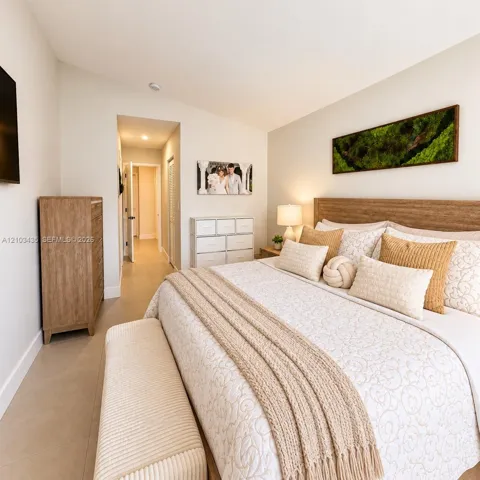 Neutral-toned interior space featuring light-colored tile flooring, a slanted ceiling, and a built-in wood-finish headboard