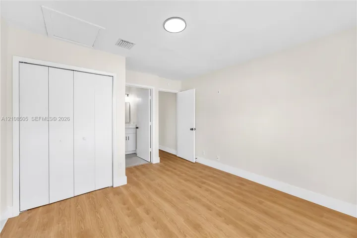 Neutral-toned interior room featuring wood-finish flooring, a multi-panel closet door, and a flush-mount overhead light fixture