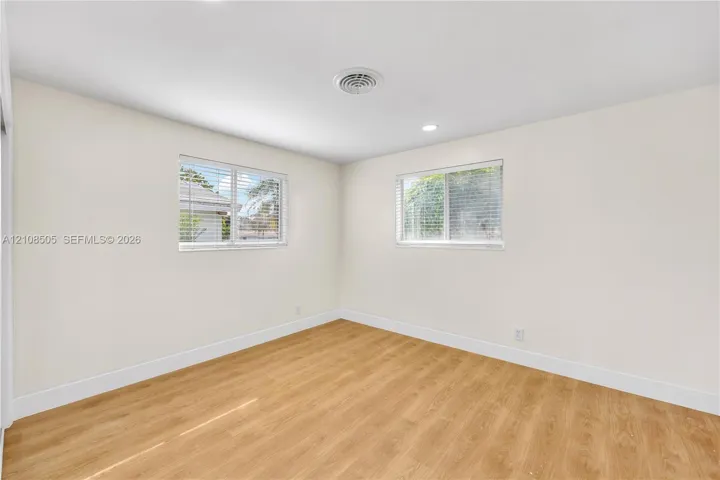 Neutral-toned interior featuring wood-finish flooring, recessed lighting, and dual windows with horizontal blinds