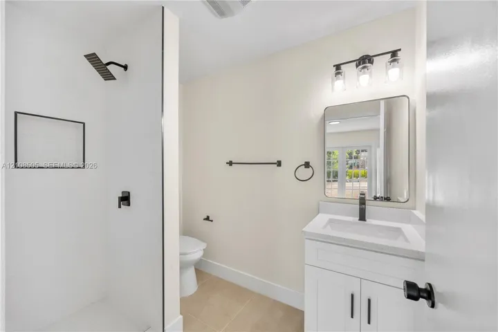 Bathroom featuring a shower with a matte black rainfall showerhead, glass enclosure, and built-in wall niche