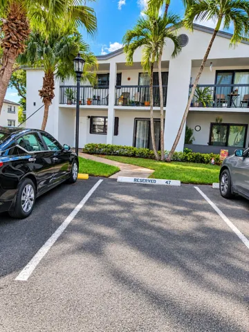 Sunlit Condo Parking Area with Palm Land